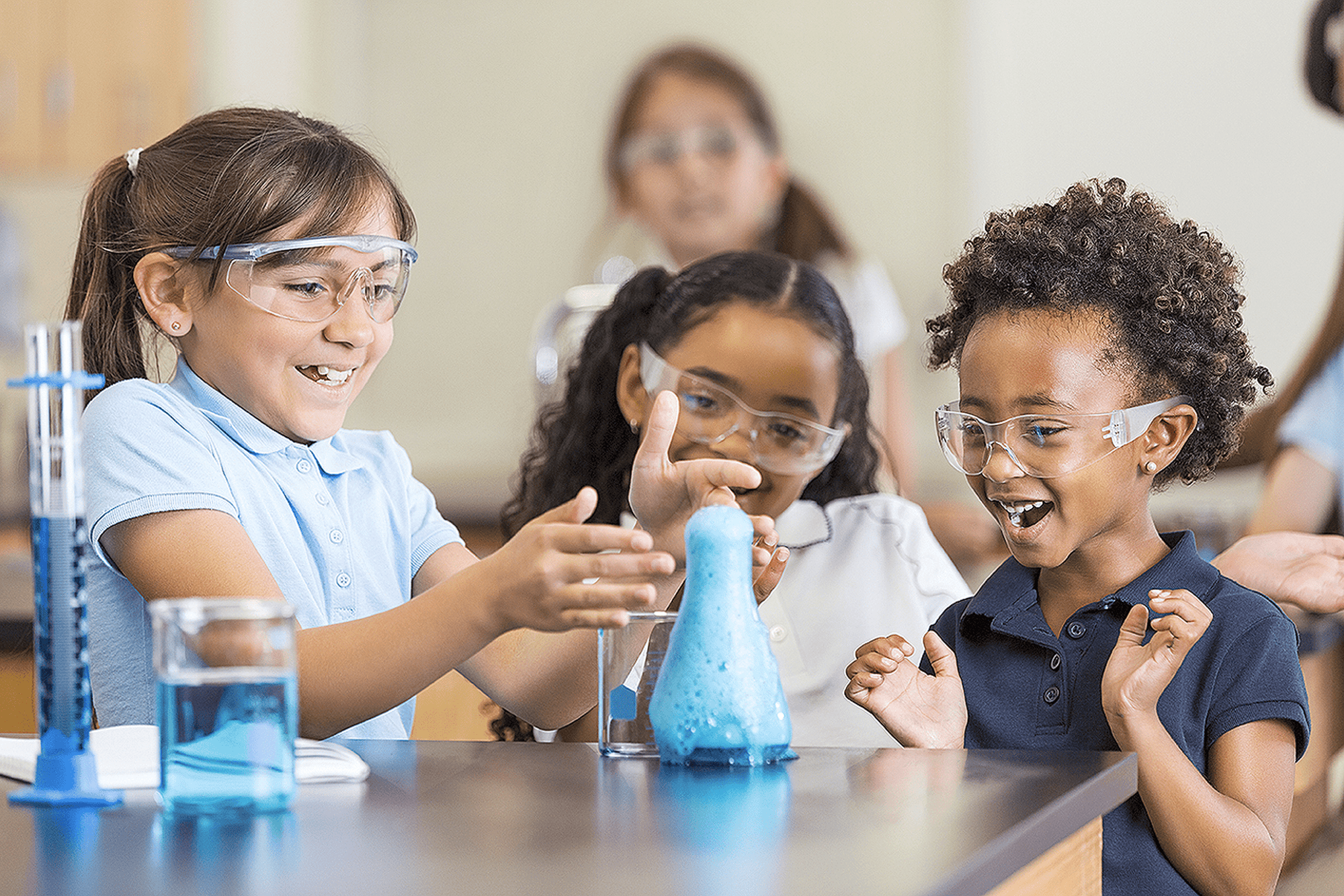 Children in a classroom setting with safety goggles conducting an experiment.