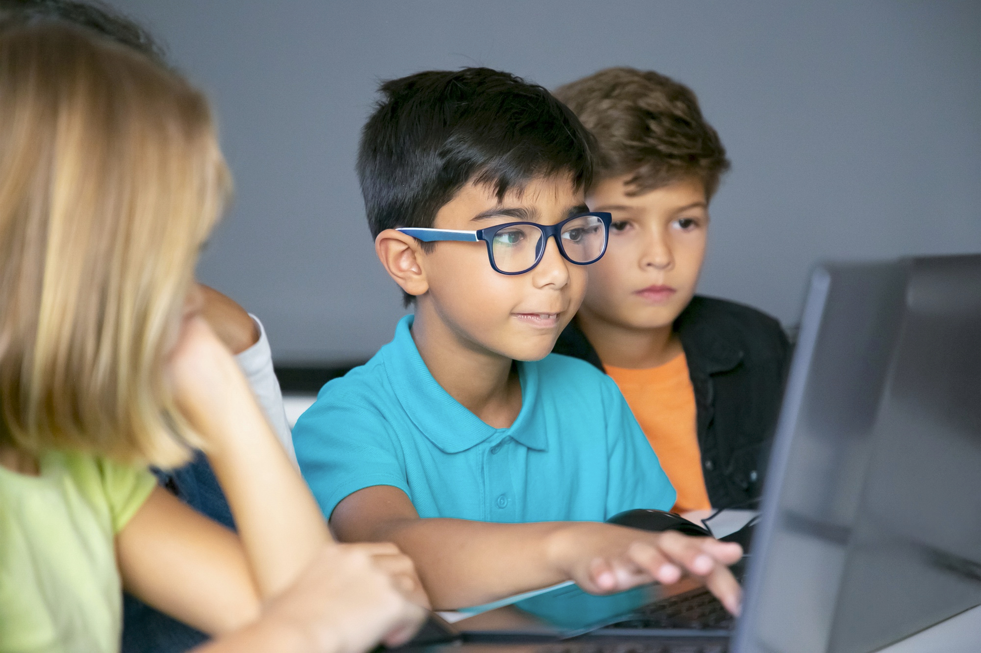 Three children looking at a laptop screen together.