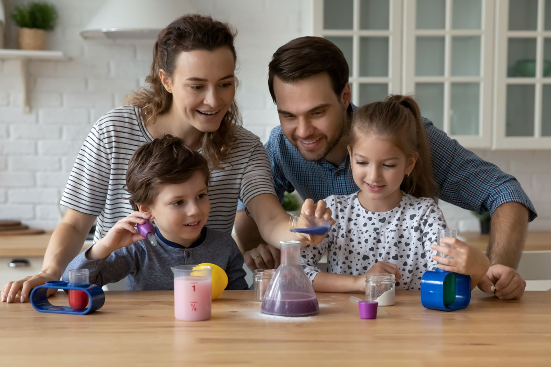 Family of four engaged in a science experiment at a table.