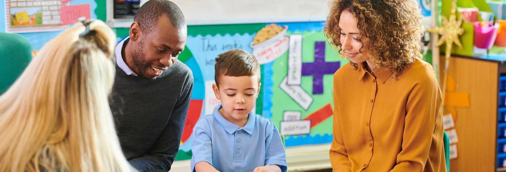 Teacher and parents interacting with a student in a classroom setting